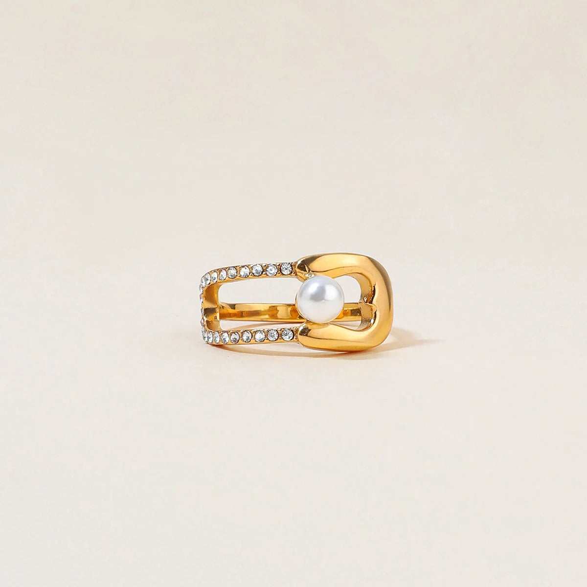 Nahaufnahme von einem goldfarbenen Ring aus Edelstahl, seitliche Ansicht, mit sichtbaren Strass-Details und einer Perle.