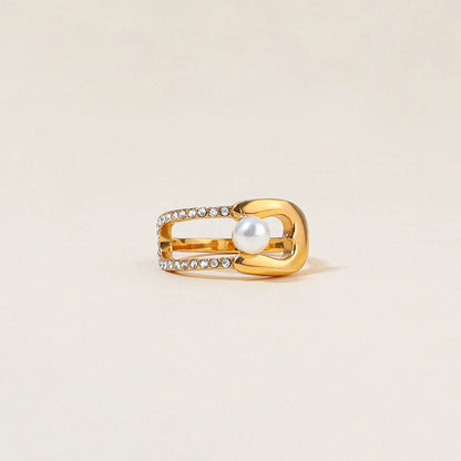 Nahaufnahme von einem goldfarbenen Ring aus Edelstahl, seitliche Ansicht, mit sichtbaren Strass-Details und einer Perle.