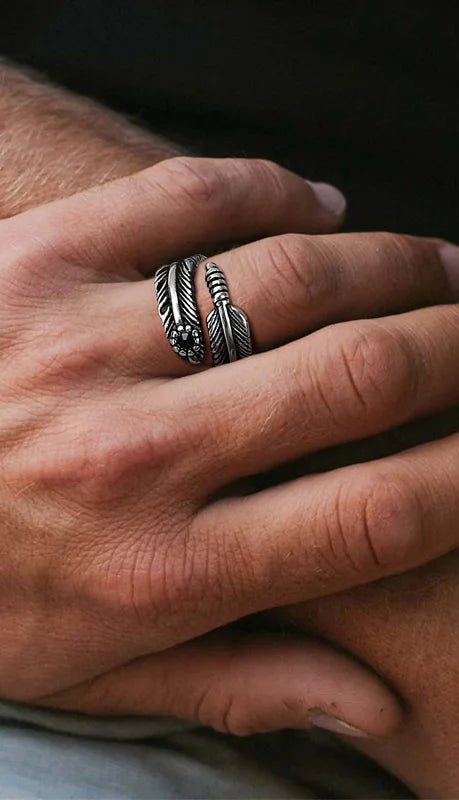 Nahaufnahme eines Mannes, der einen schmaleren silberfarbenen Edelstahl-Ring mit Federmuster und einer schwarzen Perle trägt.