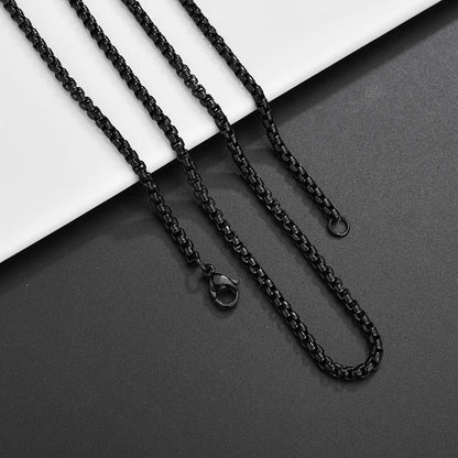 Drei schwarze Edelstahl-Boxketten in unterschiedlicher Länge, liegend auf einem schwarz-weißen Hintergrund.

