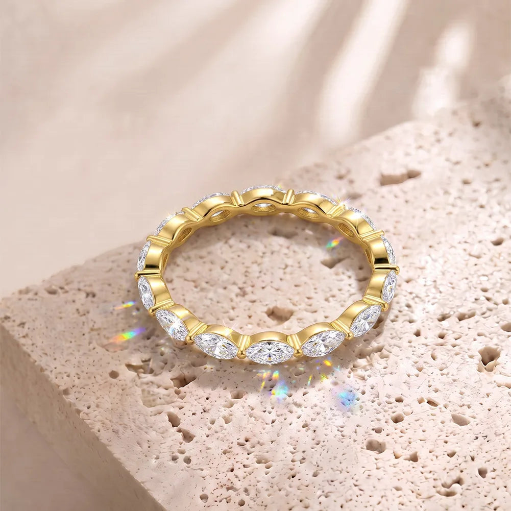 Rundum besetzter Eternity-Ring aus 14 Karat vergoldetem Silber mit strahlenden Marquise-Zirkoniasteinen auf beigem Naturstein.