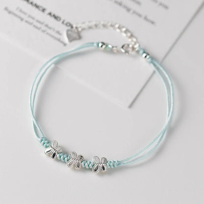 Hellblaues Kordelarmband mit drei Schmetterlingselementen aus 925er Sterling Silber elegant präsentiert.