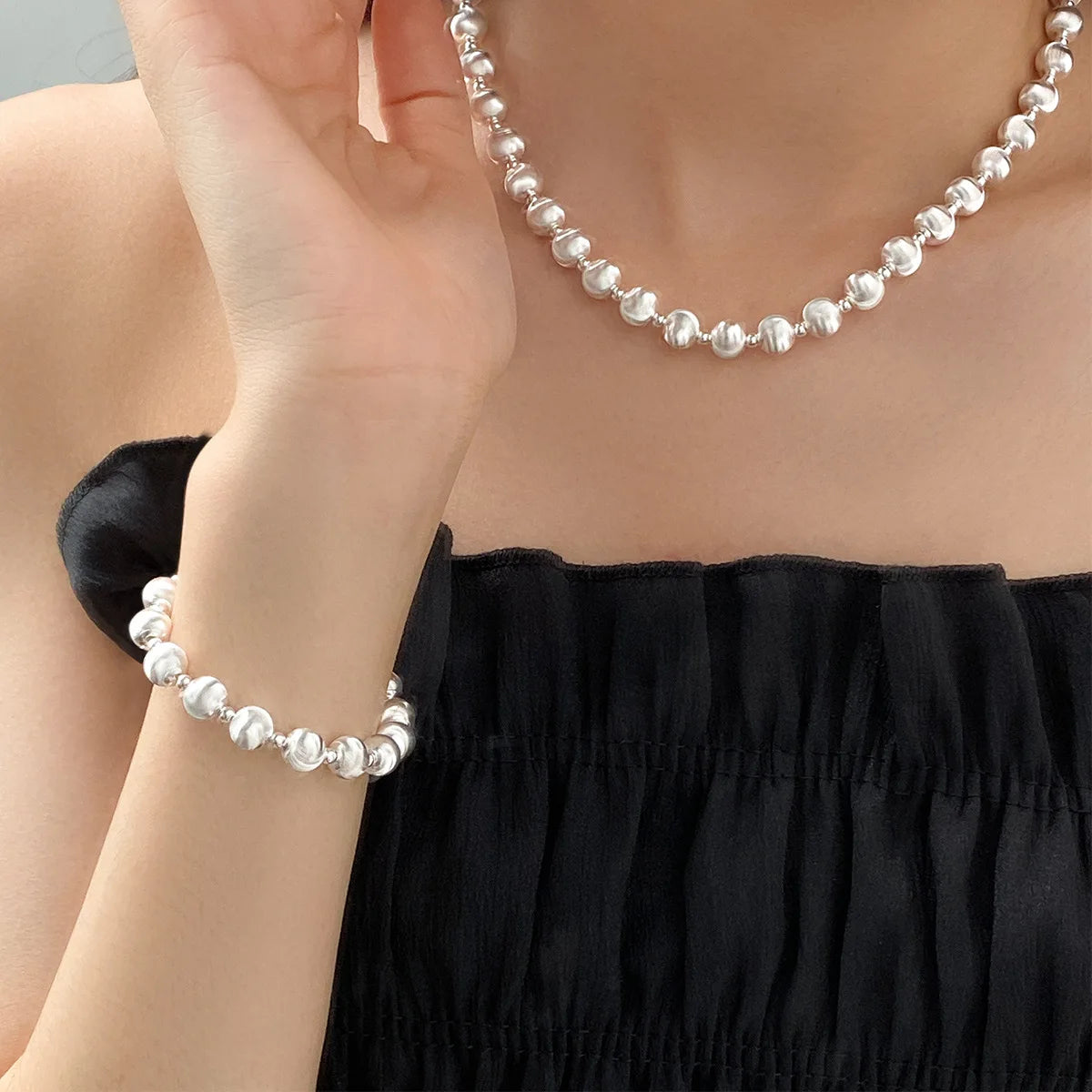 Frau trägt eine passende Kombination aus einer kurzen Halskette und einem Armband, beide aus 925er Sterling Silber mit Kugelperlen.