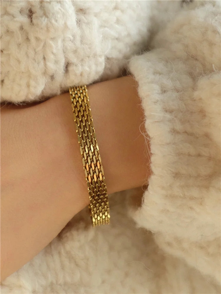 Verschlussdetail des 18K vergoldeten Bandarmbands, getragen am Handgelenk mit weichem Strickgewebe