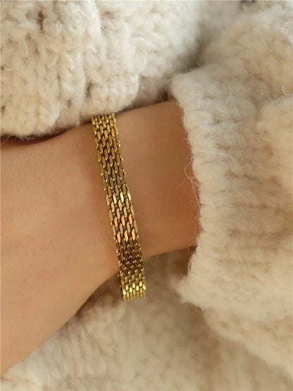 Verschlussdetail des 18K vergoldeten Bandarmbands, getragen am Handgelenk mit weichem Strickgewebe