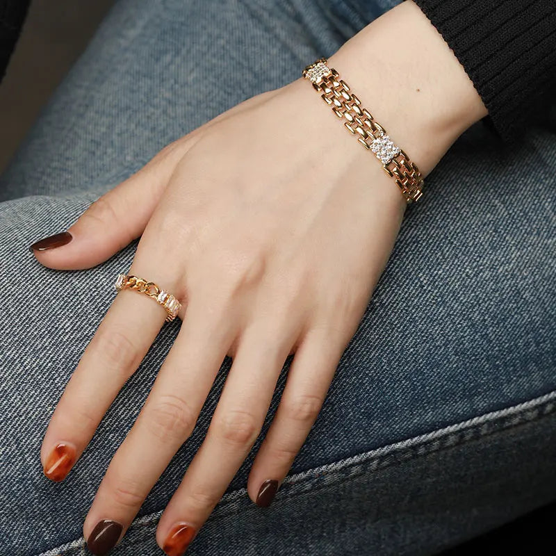 Model präsentiert das breite goldene Messing-Armband im Ketten-Look kombiniert mit einem passenden Ring an der Hand.