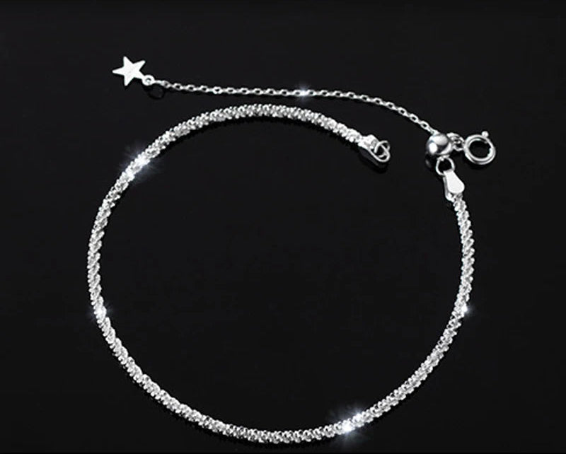 Armband aus Silber mit einer feinen, gedrehten Kette, die eine funkelnde Oberfläche (eventuell "Glitzerkette" oder "Popcornkette") bildet. Es hat einen Federringverschluss und eine Verlängerungskette, an deren Ende ein kleiner Stern-Anhänger hängt.