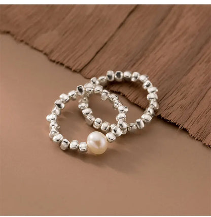 Paar von zwei strukturierten 925 Silber Ringen, eng aneinander liegend auf einem beigefarbenen Hintergrund.