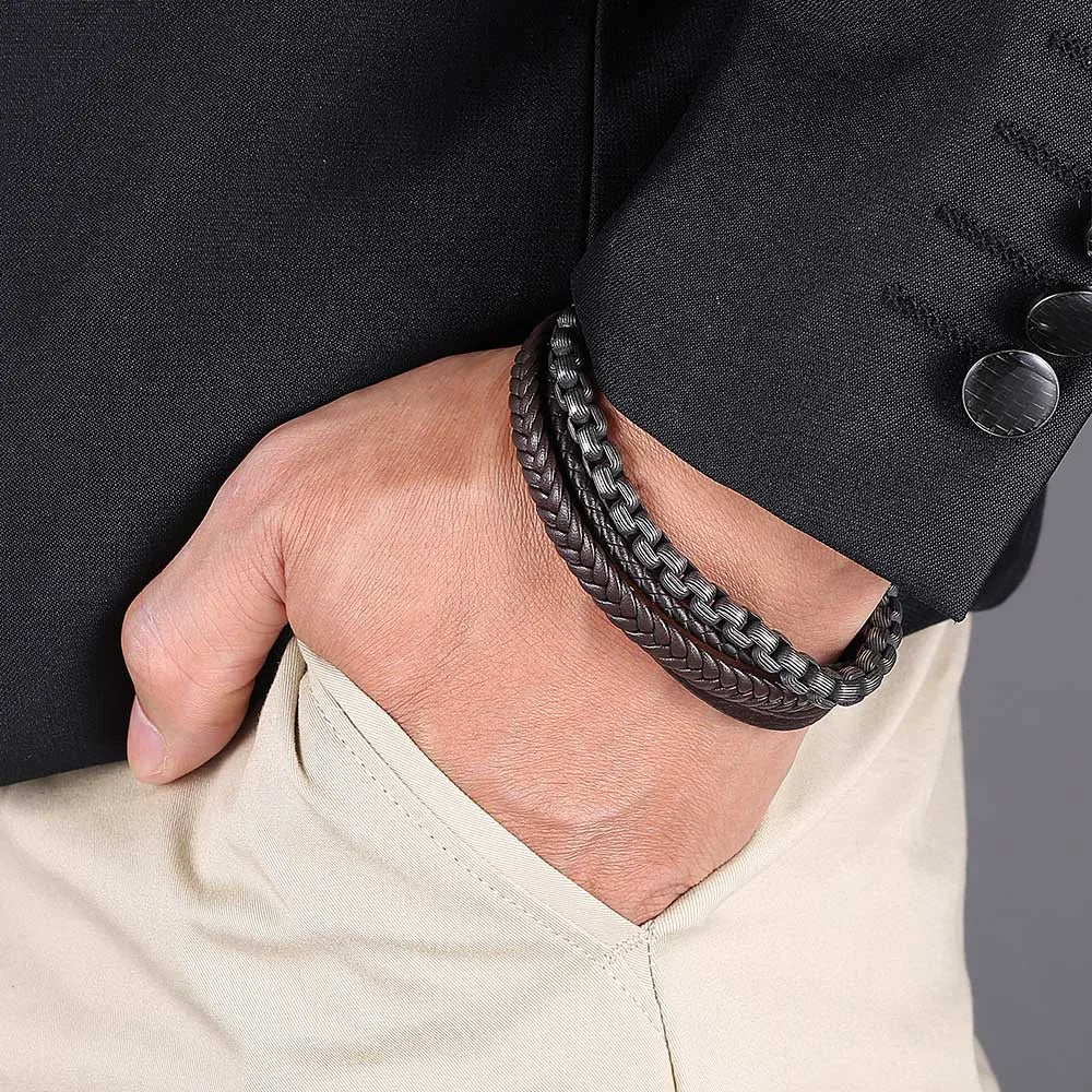 Ein Mann mit den Händen in der Hosentasche trägt das breite, mehrlagige Biker-Armband aus Leder und Edelstahl passend zum eleganten Sakko.