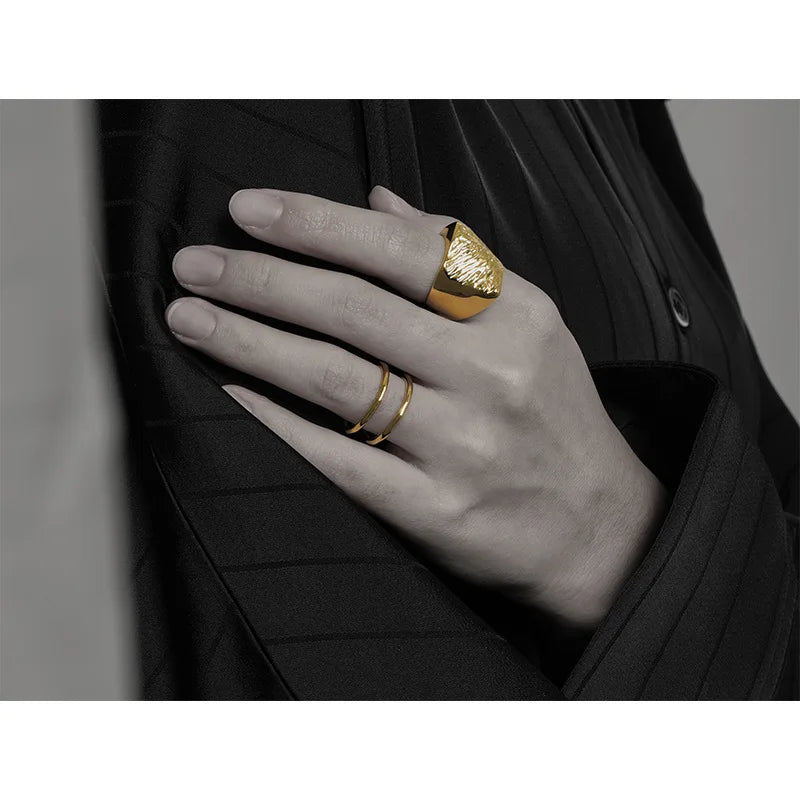 18k vergoldeter Messingring am Finger getragen, strukturierte Oberfläche, minimalistisches Design, modernes Schmuckstyling in Schwarz-Weiß