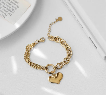 Gliederarmband aus Titan mit 18 Karat Vergoldung, zweigeteiltem Ketten-Design und Herz-Anhänger auf hellem Untergrund