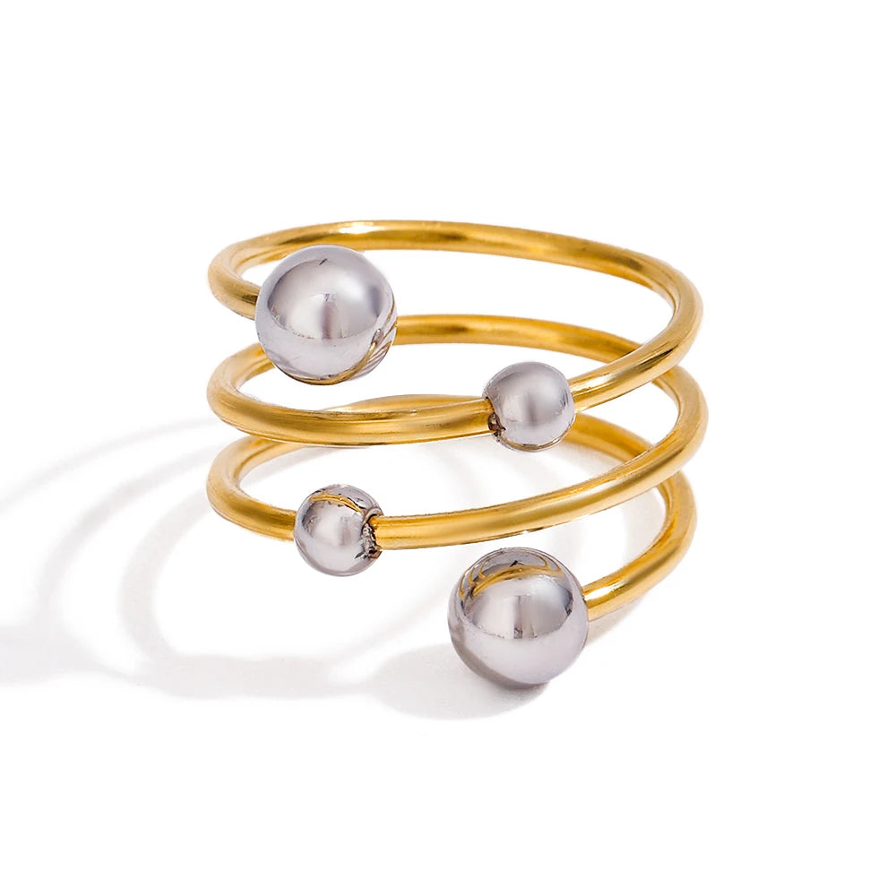 „Detailansicht der polierten Edelstahl-Kugeln auf einer dreifachen, goldfarbenen Ringschiene im minimalistischen Design.“