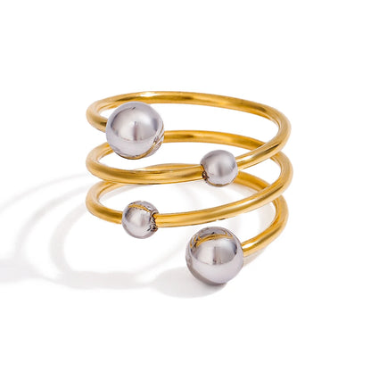 „Detailansicht der polierten Edelstahl-Kugeln auf einer dreifachen, goldfarbenen Ringschiene im minimalistischen Design.“