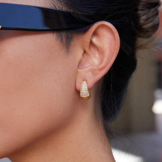 Seitliche Ansicht einer Person, die kegelförmige Creolen aus 18K vergoldetem Edelstahl mit Zirkonia-Steinen trägt.