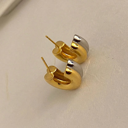 Nahaufnahme zweier dicker zweifarbiger (Gold und Silber) Creolen-Ohrringe mit Steckverschluss.
