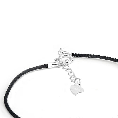 Detailaufnahme des Verschlusses eines Armbands mit schwarzem Textilband. Der Verschluss besteht aus einem Herz-Anhänger und einem Karabiner aus 925er Silber.