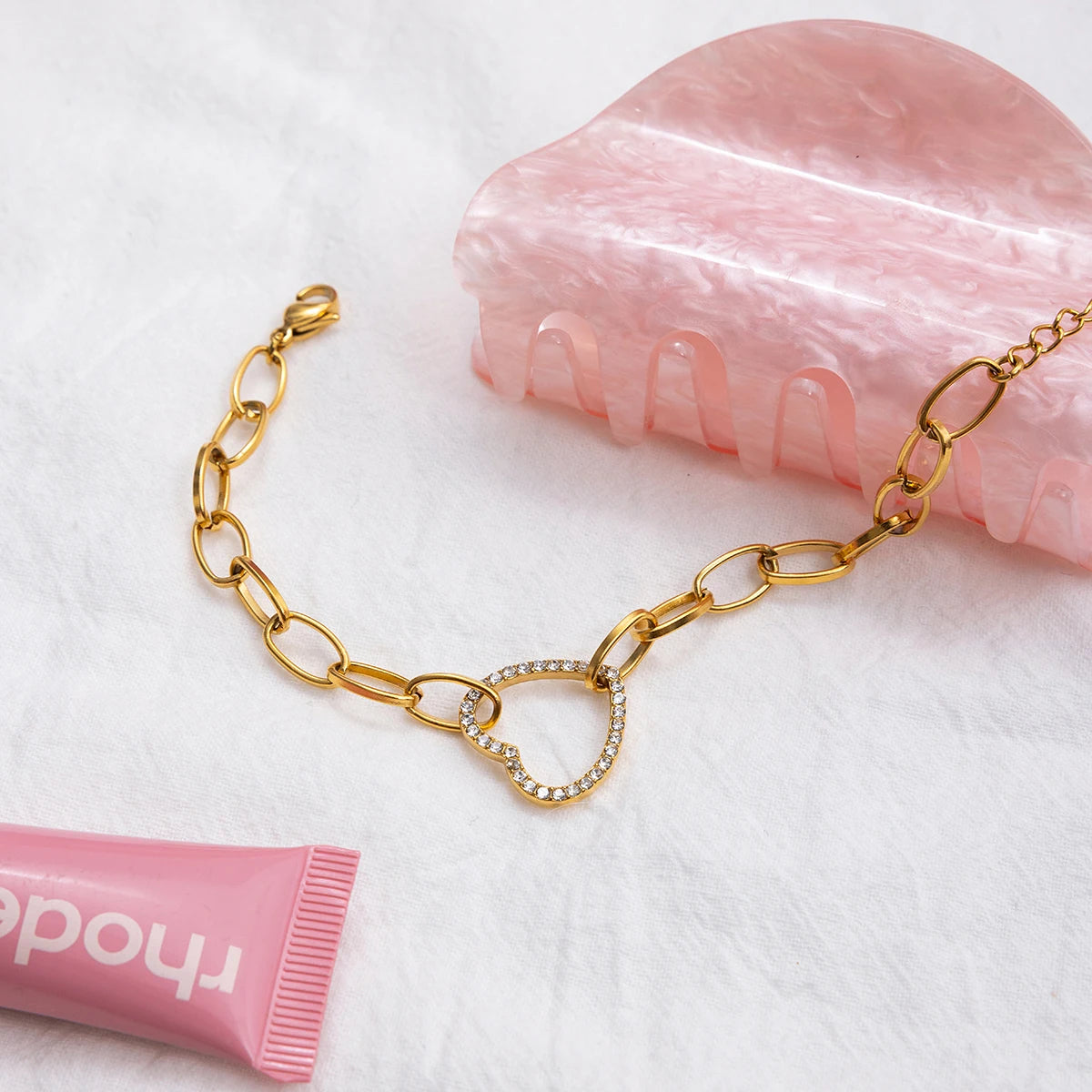 Modernes Damen-Armband mit Herz-Glied und Zirkonia-Besatz stilvoll arrangiert mit Lipbalm und Haarspange