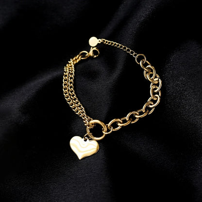 Edles goldenes Titan-Armband mit Herz-Charm im Kontrast präsentiert auf schwarzem Seidenstoff