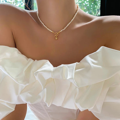 Zarte Choker-Halskette aus kleinen, unregelmäßig geformten Naturperlen mit glänzendem Gold-Verschluss als modisches Statement.