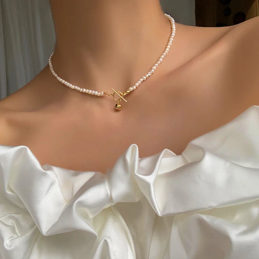 Elegante Halskette aus echten natürlichen Perlen mit einem dekorativen Knebelverschluss (T-Bar) aus 18K vergoldetem Messing.