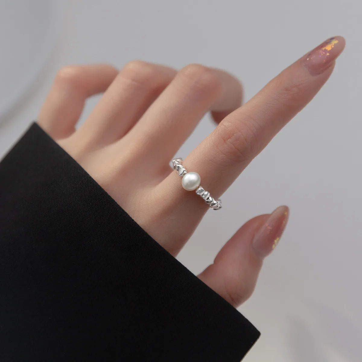  Nahaufnahme einer Hand, die den 925 Silber Ring mit Acrylperle trägt. Der Ring ist im Fokus und sitzt eng um den oberen Teil des Fingers.