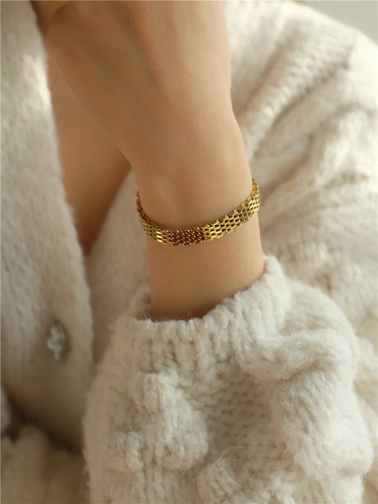 18K vergoldetes Fischgräten Kettenarmband für Damen, getragen an einem Handgelenk mit cremefarbenem Strickpullover