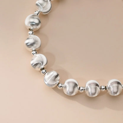 Detailaufnahme einer Kugelperlen-Halskette aus 925er Sterling Silber, die mattierte und glänzende Perlen im Wechsel zeigt.