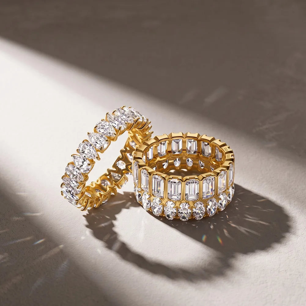 Elegante Stacking-Kombination im Sonnenlicht: Vergoldeter Tropfenschliff-Eternity-Ring kombiniert mit einem Smaragdschliff-Ring