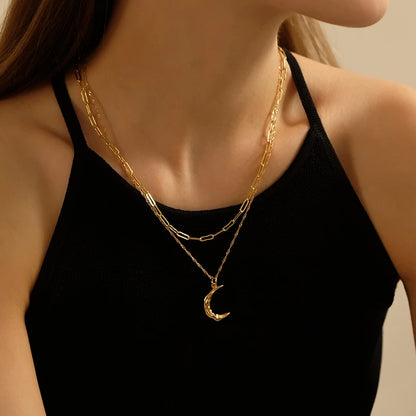 Zweireihige Layering-Halskette aus 18K vergoldetem Messing mit einer Paperclip-Gliederkette und einem Sichelmond-Anhänger an einer Frau im schwarzen Top.