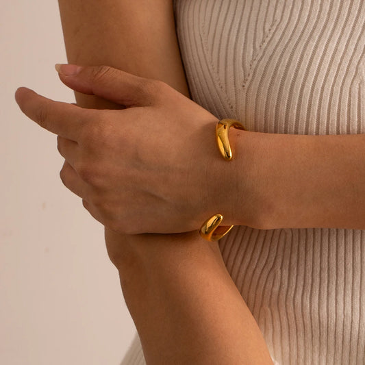 Frau trägt das stilvolle Armband Ayva - klassischer Cuff-Armreif in Gold-Optik

