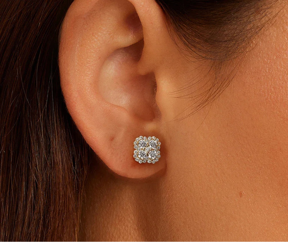 Nahaufnahme eines weiblichen Ohrs, das einen kleeblattförmigen Ohrstecker aus 14K vergoldetem Silber und Zirkonia trägt.