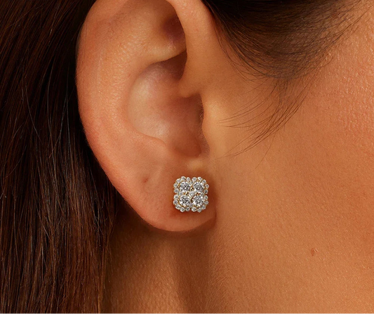 Nahaufnahme eines weiblichen Ohrs, das einen kleeblattförmigen Ohrstecker aus 14K vergoldetem Silber und Zirkonia trägt.