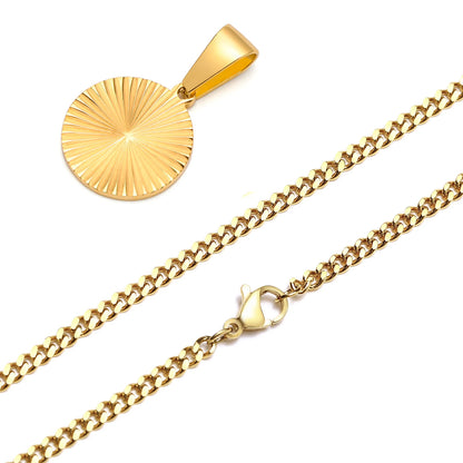 Goldfarbene, grobgliedrige Edelstahl-Halskette (Curb-Kette) mit einem runden Anhänger, der ein eingraviertes, diagonales Sonnenstrahl-Muster aufweist. Der Karabinerverschluss der Kette ist deutlich sichtbar.