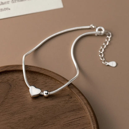 Schlichtes Schlangenarmband aus 925er Silber mit verstellbarer Verlängerungskette und Federringverschluss elegant auf einem Holzschälchen arrangiert