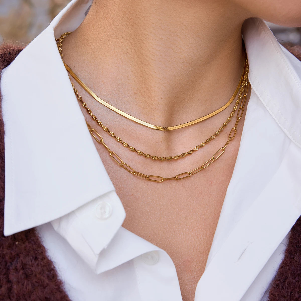 Detailaufnahme des dreireihigen goldenen Halsketten-Sets aus 18K vergoldetem Edelstahl am Dekolleté.
