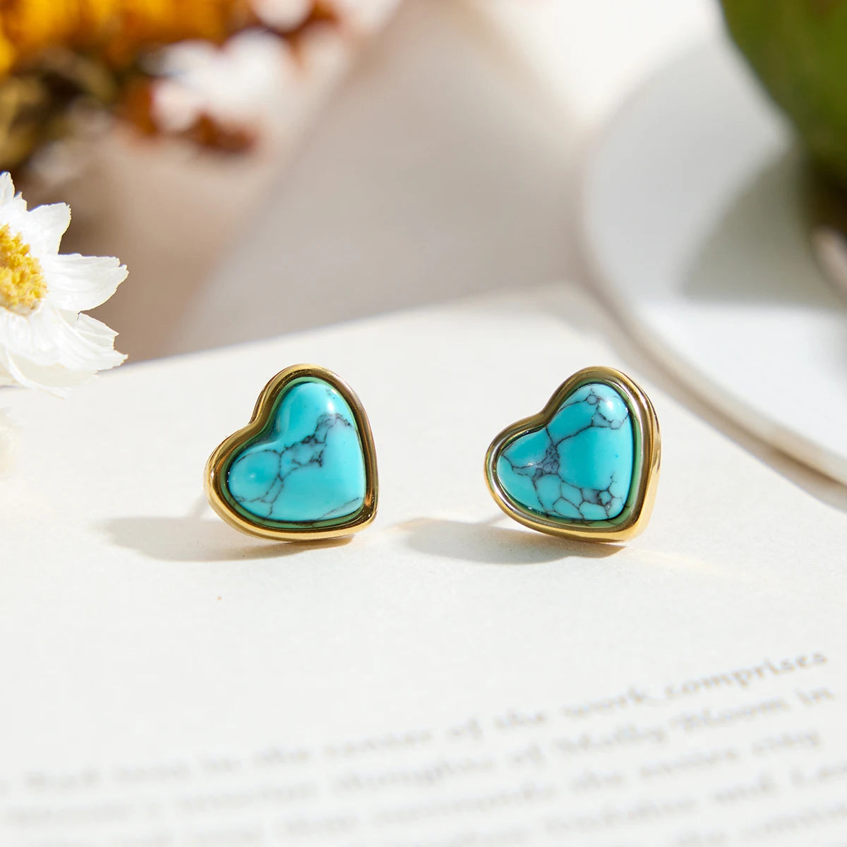 Paar Herz-Ohrstecker aus Edelstahl mit 18K PVD Vergoldung und blauem Türkisstein auf Buch