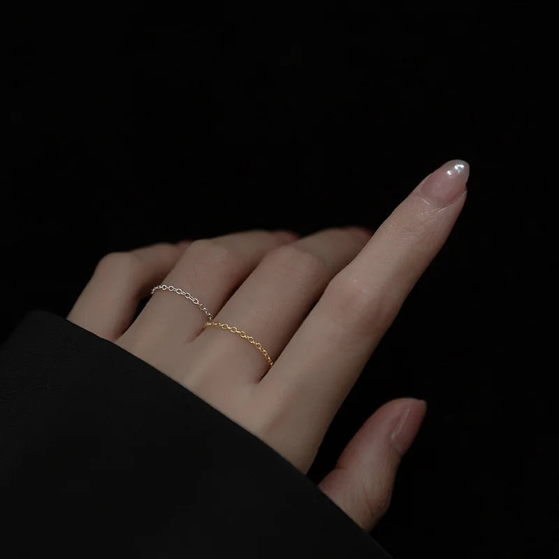 Model trägt die zarten Kettenringe aus 925er Silber mit Platin- und 18K Goldplattierung gestapelt am Finger.