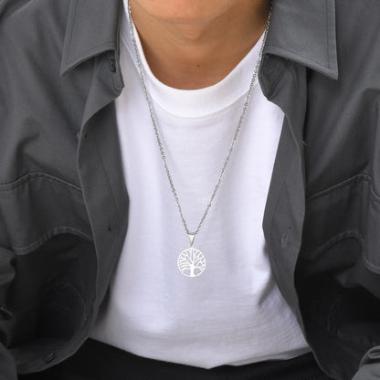 Silberfarbene Edelstahlkette mit Lebensbaum-Medaillon, getragen von einem Mann über einem weißen T-Shirt und offenem, dunklem Hemd, mittlere Ansicht.