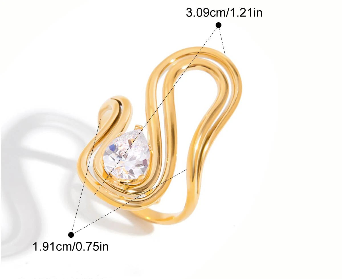 Grafische Darstellung eines goldenen Rings mit 18K PVD-Vergoldung. Er hat ein geschwungenes, unregelmäßiges Design und ist mit einem großen, klaren Zirkonia Stein besetzt. Die Maße sind ebenfalls angegeben mit einem Innendurchmesser von 1,91 cm und einer Breite von 3,1 cm.
