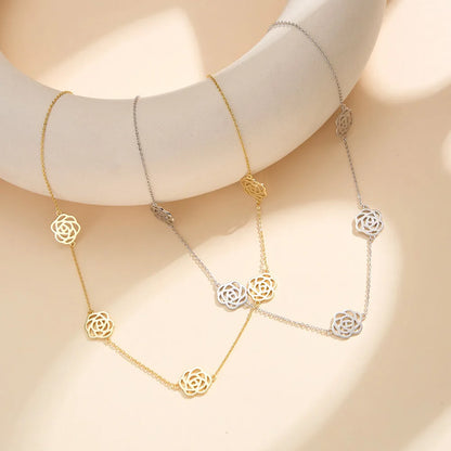 Zwei filigrane Ketten mit Rosenblüten-Anhängern im direkten Vergleich – eine in 925er Sterling Silber und eine in einer vergoldeten Ausführung (14K Gold über Sterling Silber) – präsentiert auf minimalistischen weißen Podesten.